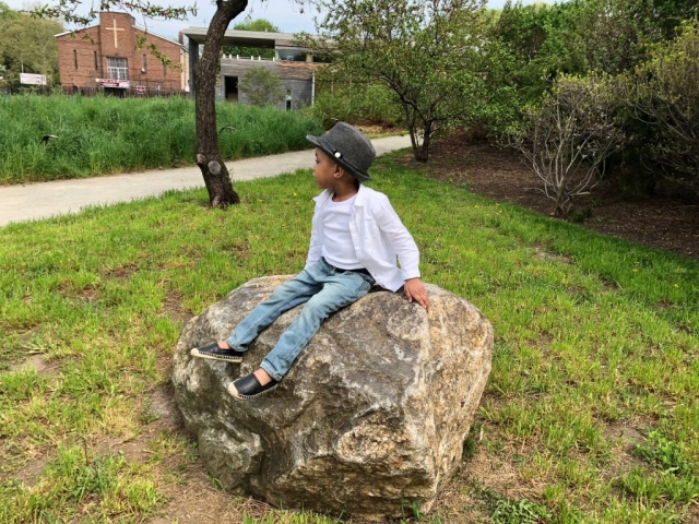 Lucien sitting on boulder at Weeksville Heritage Center